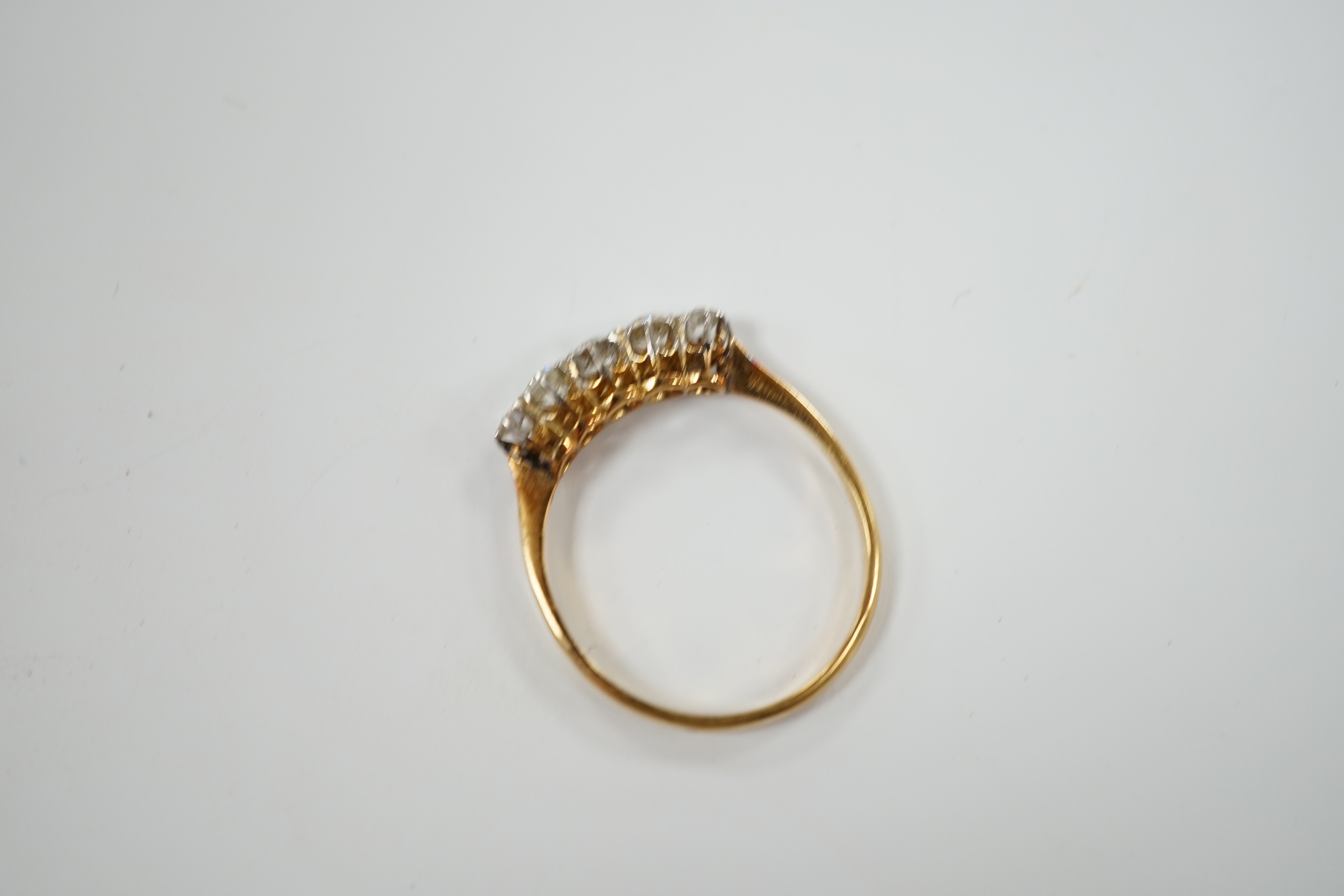 An 18ct, pt. and graduated five stone diamond set half hoop ring, size Q, gross weight 2.4 grams.
